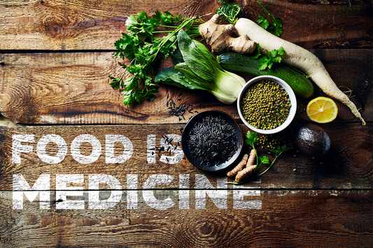 Zizania Aquatica and lentils are separated in different bowls, surrounded vegetables on a wooden surface which has the text "Food is medicine" on it.