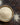 Grains of Fonio is in a cheramic bowl, there are seeds around it on a brown-rustic surface